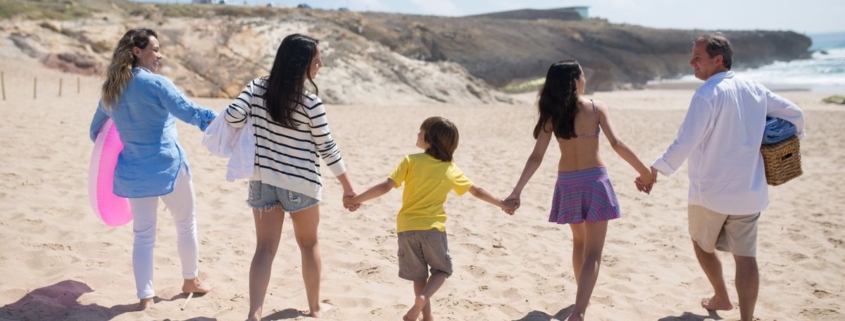 Familia caminando de la mano por la playa durante las vacaciones de verano